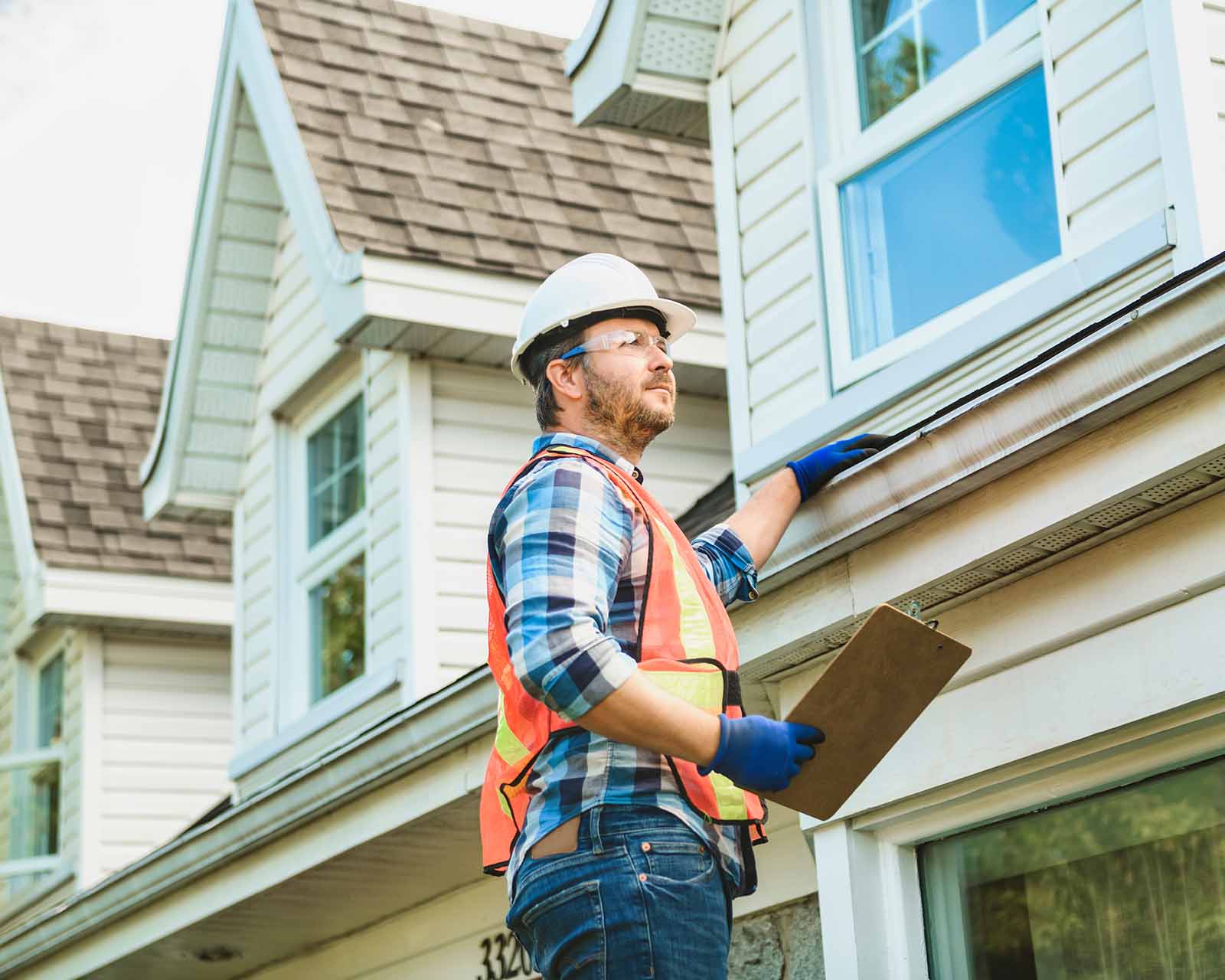 contractor inspecting gutters outside home