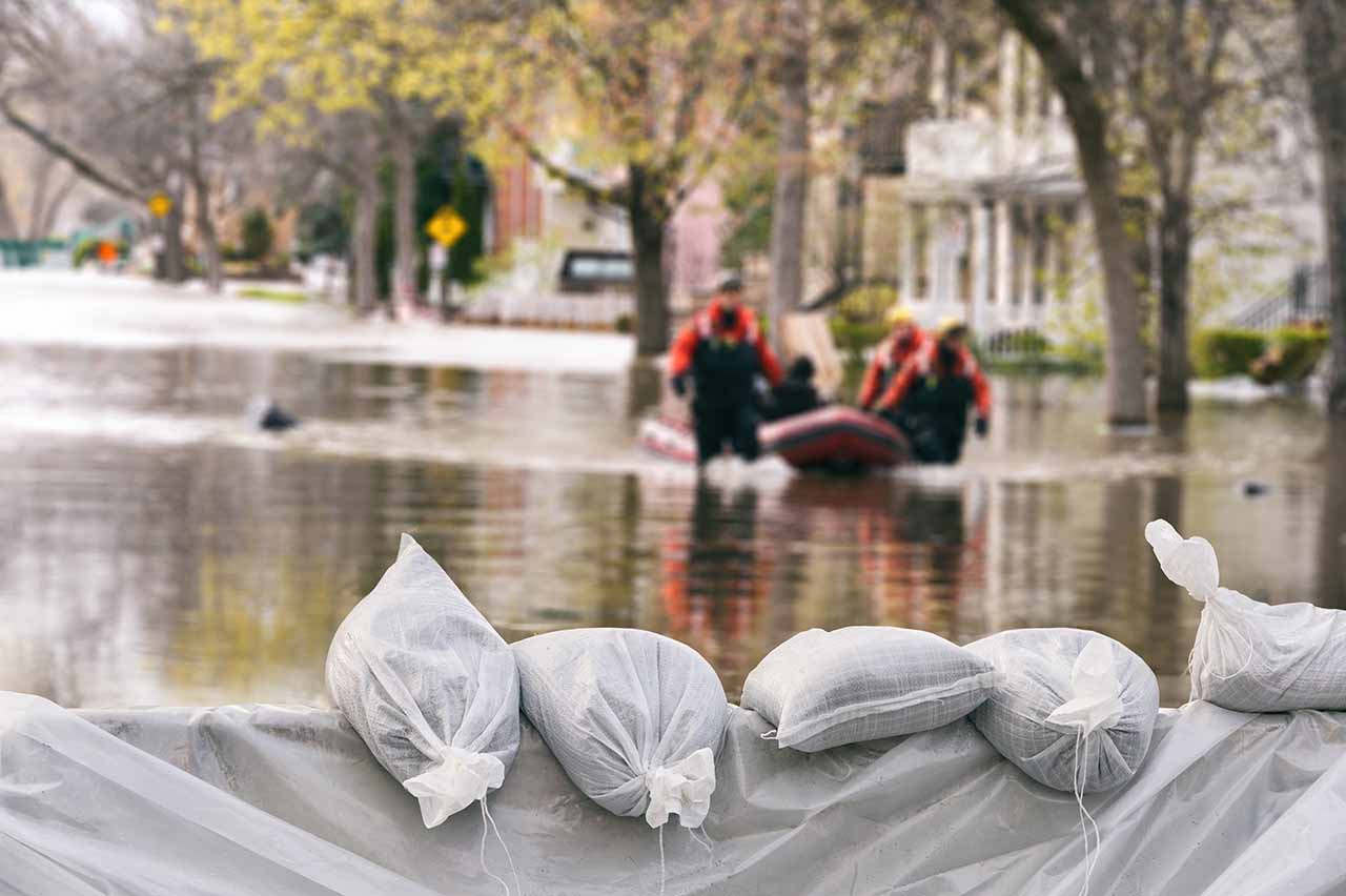 emergency crews helping people during flooding with boat wading through water